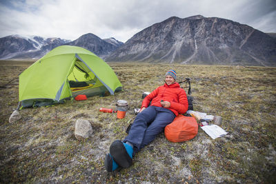 Mountaineer relaxes outside of tent during climbing trip.