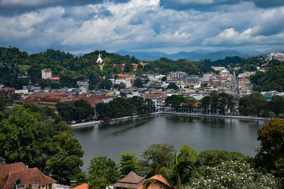 Scenic view of river and houses in town against sky