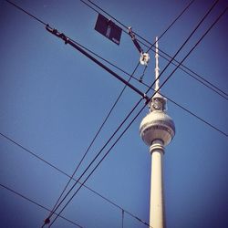 Low angle view of electricity pylon against blue sky