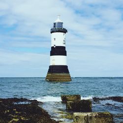 Lighthouse by sea against sky