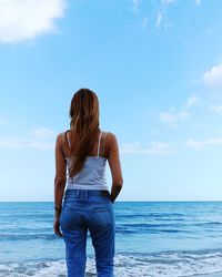 Rear view of man standing in sea against sky