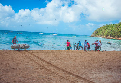 Panoramic view of people on beach against sky