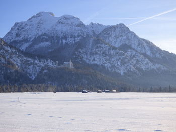 Scenic view of snow covered field by mountains against sky