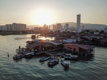 High angle view of buildings by sea against sky during sunset