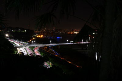 Illuminated bridge over river in city at night