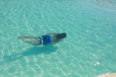 Rear view of young man swimming in pool