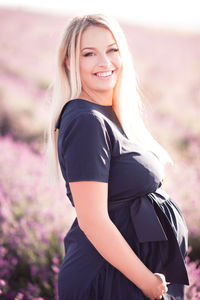 Pregnant woman standing in field on sunny day