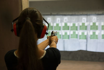 Rear view of woman shooting at target