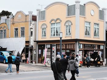 People walking on street against buildings in city