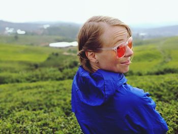 Young woman wearing sunglasses standing in farm against sky