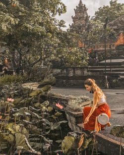 Full length of woman crouching on footpath