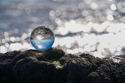 Close-up of crystal ball on rock against sky