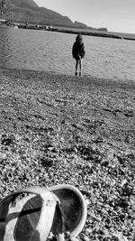 Low section of man standing on beach against sky