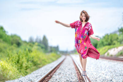 Portrait of a smiling young woman standing on railroad track