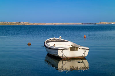 Boat moored in sea against clear blue sky