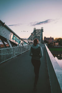 Rear view of man and woman standing on suspension bridge