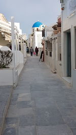 Rear view of people walking on footpath amidst buildings