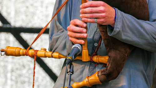 Midsection of man playing musical instrument against wall