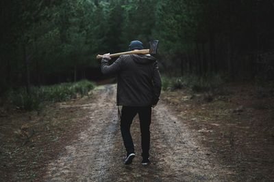 Rear view of man with axe in forest