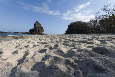 Surface level of rocks on beach against sky