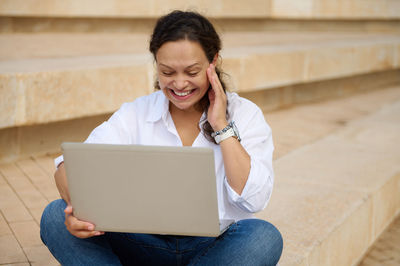 Businesswoman using laptop while sitting on steps