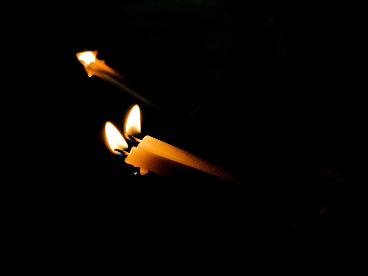 CLOSE-UP OF BURNING CANDLES IN DARKROOM