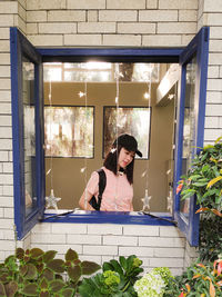 Young woman standing by decoration and window