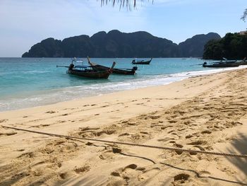 Boats moored on beach against sky