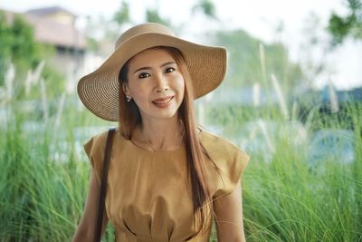 Portrait of smiling young woman wearing hat on field