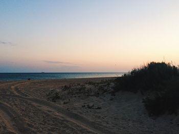 Scenic view of beach against clear sky during sunset