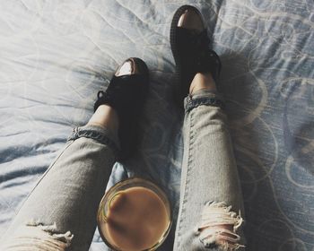 Low section of woman having coffee on bed