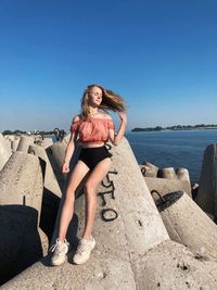 Portrait of young woman sitting on rock at beach