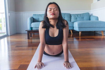 Young woman doing yoga on yoga mat at home