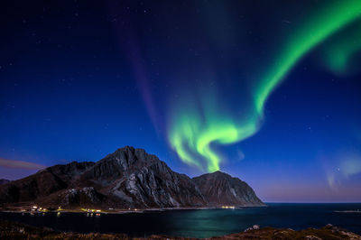 Scenic view of sea and mountains against sky at night