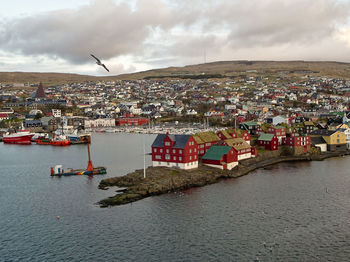 Aerial view of townscape by sea against sky