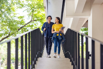Two asian university students walking and conversing to class in a magnificent campus building