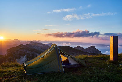 Tent on field against sky during sunset