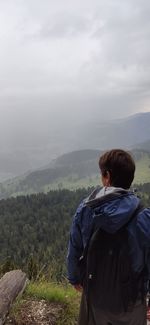 Rear view of man looking at mountain against sky