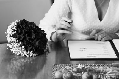 Midsection of woman reading book on table