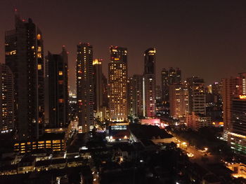 Illuminated buildings in city against sky at night