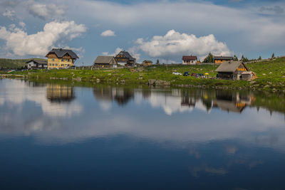 Scenic view of houses by water against sky