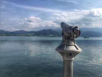 Close-up of coin-operated binoculars by sea against sky