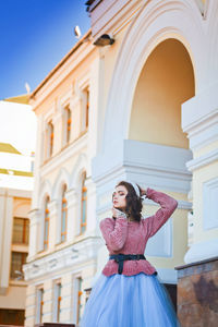 Young woman posing in front of building