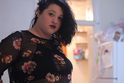 Portrait of overweight young woman standing at home