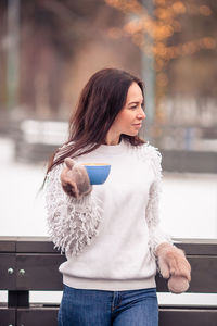 Young woman looking away while standing outdoors