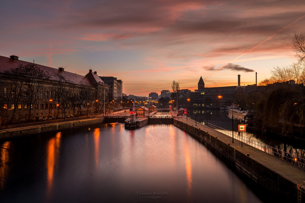 BRIDGE OVER RIVER WITH BUILDINGS IN BACKGROUND