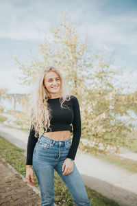 Portrait of smiling young woman against tree