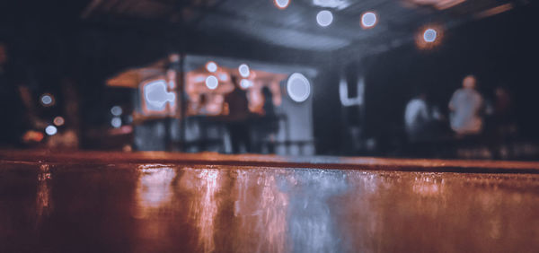 Reflection of people on wet table in illuminated restaurant