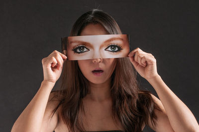 Portrait of young woman against black background
