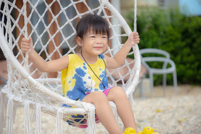 Cute girl sitting on swing in playground